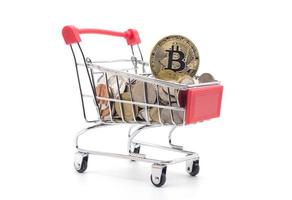 Bitcoin y monedas de oro en carrito de compras sobre fondo blanco. foto