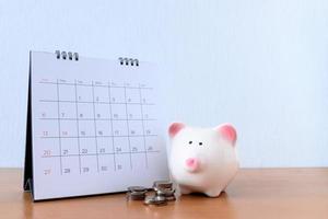 Calendar With Days and piggybank on wood table photo