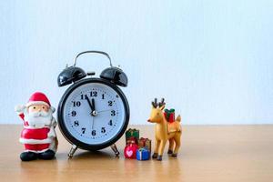 santa claus y reloj, ciervo y regalo en la mesa. feliz año nuevo y concepto de navidad foto