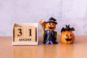 Wooden calendar block disrupted show date 31 october halloween day and toy pumpkin on wooden background. Halloween concept photo