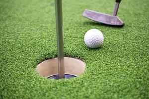 pelota de golf y palo de golf sobre césped artificial. foto