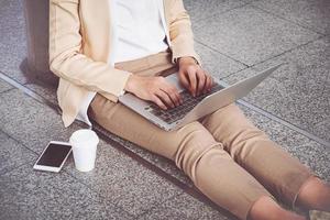 Businesswoman in high heels sitting on floor with computer in her lap photo