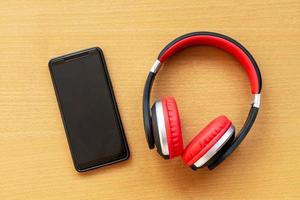 auriculares y reloj despertador y teléfono inteligente en el escritorio de madera. concepto musical foto