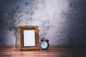 Picture frame and flowers and clock on wooden table. Poster product design styled photo