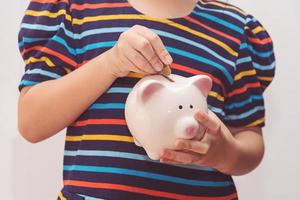 Cute little girl putting coin into piggy bank photo