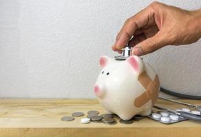 Doctor Holding Stethoscope to Piggy Bank photo