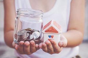 Small kid hands holding house and coins photo