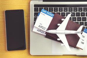 teléfono inteligente cerca de la computadora portátil y el avión en la mesa. concepto de reserva de boletos en línea foto