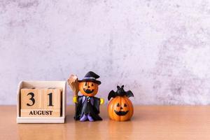 Wooden calendar block disrupted show date 31 october halloween day and toy pumpkin on wooden background. Halloween concept photo