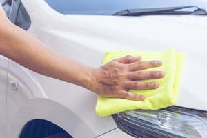 Hombre limpiando el coche con un paño de microfibra foto