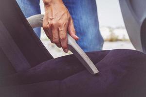 hombre limpiando el interior del coche con aspiradora foto