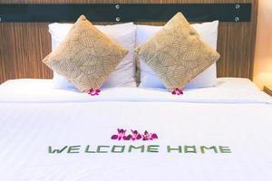bed with pillows decorated with tropical flowers and an inscription welcome. Theme of hotel service