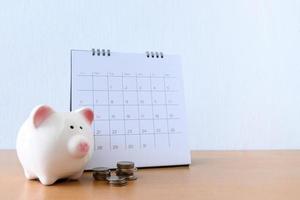 Calendar With Days and piggybank on wood table photo