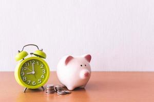 Piggy bank, alarm clock and coins. for growing business. time to saving concept. photo