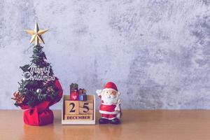 Block calendar date December 25 calendar and Christmas decoration - Santa Clause, tree and gift on wooden table. Christmas and Happy new year concept photo