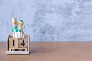 pareja de bodas en miniatura con calendario de madera 14 de febrero. día de San Valentín foto