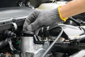 Un mecánico está abriendo el tapón de aceite del motor de un automóvil. foto