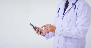 joven médico hombre vestido con una bata blanca usando un teléfono inteligente foto