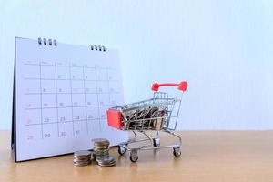 Calendar with days and Cart supermarket on wood table. shopping concept photo