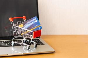 tarjeta de crédito y carrito de supermercado en mesa de madera. concepto de compras