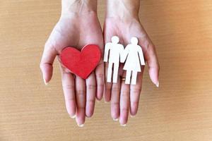 manos de mujer sosteniendo el corazón rojo y la familia de íconos, cuidado de la salud, concepto de seguro familiar foto