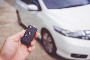 hombre que sostiene las llaves del coche con el coche en el fondo foto