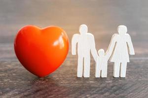 corazón rojo y familia de iconos en el escritorio de madera. concepto de seguro médico foto