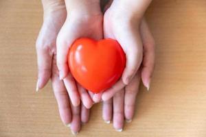 mother and daughter hands holding red heart, health care, donate and family insurance concept photo