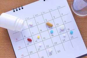 bunch of different pills on a calendar background. concept Healthcare photo