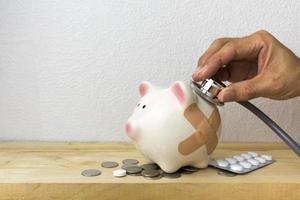 Doctor Holding Stethoscope to Piggy Bank photo