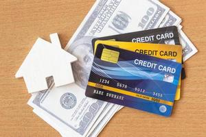 House, credit cards and dollars on wooden table. Concept of saving money photo