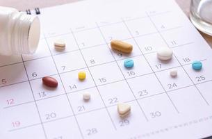 bunch of different pills on a calendar background. concept Healthcare photo