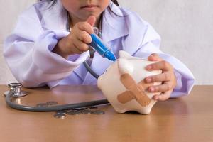 Asian girl playing as a doctor care Piggy Bank photo