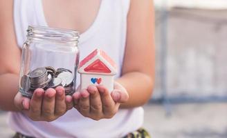 Small kid hands holding house and coins photo