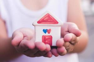 Small kid hands holding house photo