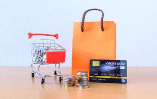 Cart supermarket and orange paper bag on wood table. shopping concept photo