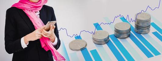 Arab businesswoman with stack of money coins and growth graph photo
