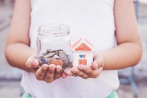 Small kid hands holding house and coins photo