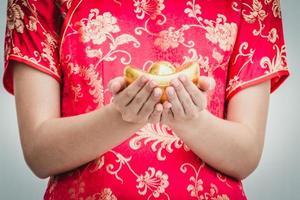 Asian woman with cheongsam holding gold. Chinese new year. photo