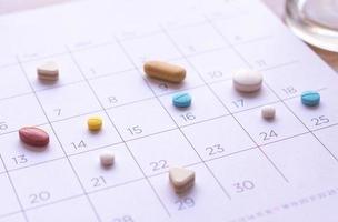 bunch of different pills on a calendar background. concept Healthcare photo