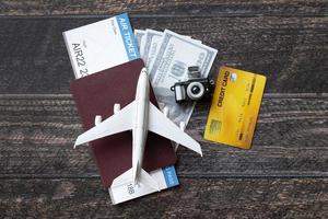 avión de juguete, billete de avión, tarjetas de crédito, dólares y pasaporte sobre mesa de madera. concepto de viaje foto