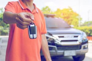 Man holding car keys with car on background photo