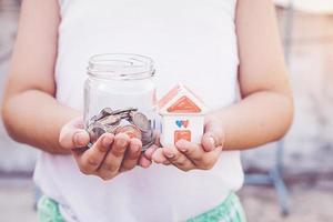 Small kid hands holding house and coins photo