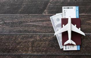 avión de juguete, billete de avión, tarjetas de crédito, dólares y pasaporte sobre mesa de madera. concepto de viaje foto