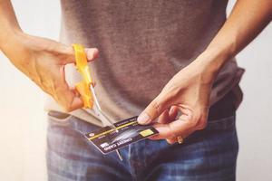 Man cutting credit card with scissors. photo