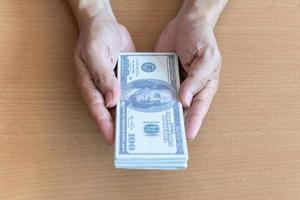 Man hands holding 100 dollar bills on wooden table. Wealth and financial concept photo