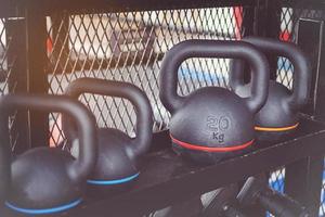 juego de mancuernas negras. muchas pesas de metal en el estante en el gimnasio, concepto de equipo de entrenamiento con pesas. foto