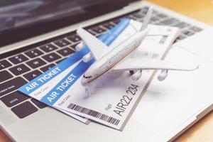 computadora portátil y avión y boleto en la mesa. concepto de reserva de boletos en línea foto