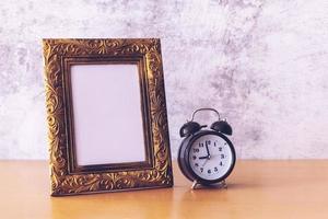 retro style Picture frame and alarm clock on wooden table. Poster product design styled photo