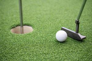pelota de golf y palo de golf sobre césped artificial. foto